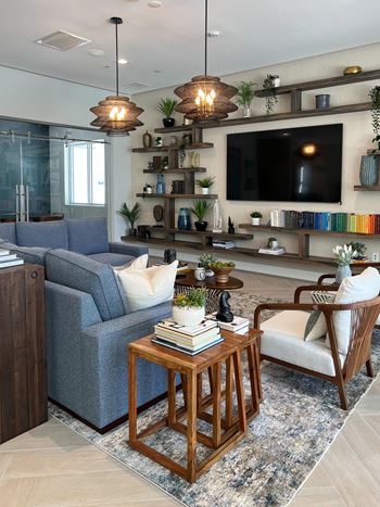 A living room with a grey couch, a wooden coffee table, a white chair, and a TV on a wooden stand.